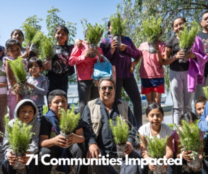 children holding tree seedlings with adult in the middle at reforestation event